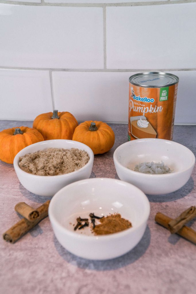 Ingredients to make the pumpkin spice syrup. Pumpkin puree, sugar, fresh ginger, whole cloves, cinnamon sticks and nutmeg.