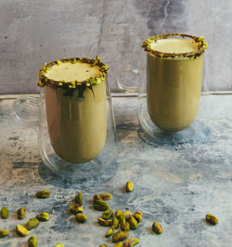 Vegan pistachio latte with pistachios in front of the glasses.